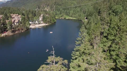 Man paddle boarding on a pristine mountain lake on sunny day with his dog, stand Stock-Footage 251684155