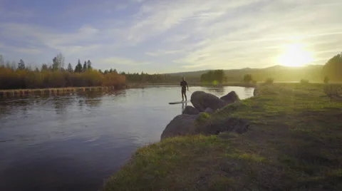 Man paddle boards during a sunset Stock Footage 62843678