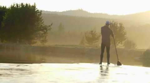 Man paddles on board down river in slow motion Stock Footage 64363062