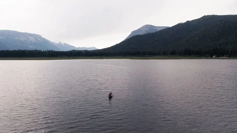 Man Paddles canoe through pristine mountain lake in the Cascades of Washington Vidéo 111391539
