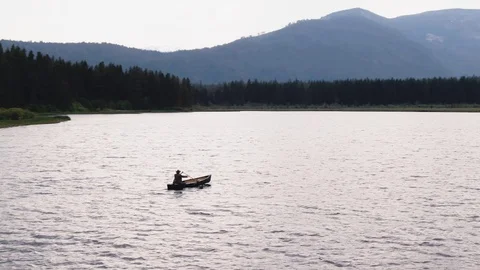 Man Paddles canoe through pristine mountain lake in the Cascades of Washington Stock-Footage 111391640