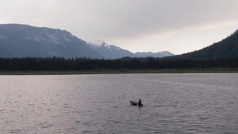 Man Paddles canoe through pristine mountain lake in the Cascades of Washington Stock Footage 111391673