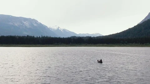 Man Paddles canoe through pristine mountain lake in the Cascades of Washington Stock Footage 111391759
