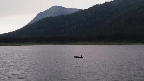 Man Paddles canoe through pristine mountain lake in the Cascades of Washington Stock Footage 111391833