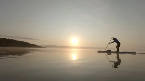 Man paddling on stand up paddle board at dawn. SUP boarding Video stock 242947120