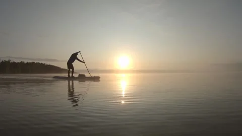 Man paddling on stand up paddle board at dawn. SUP boarding Video stock 243428402