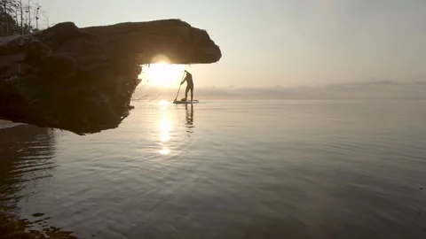 Man paddling on stand up paddle board at dawn. SUP boarding Stock Footage 243428426