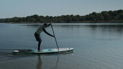 Man paddling on stand up paddle board on lake. SUP boarding Stock Footage 243428938
