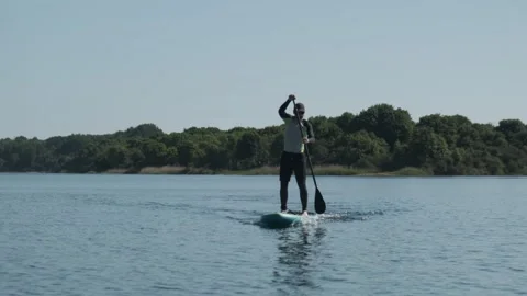 Man paddling on stand up paddle board on lake. SUP boarding Stock Footage 243428993