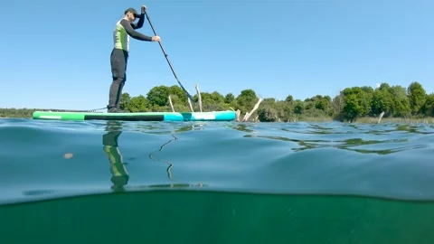 Man paddling on stand up paddle board on lake. Half underwater shot. SUP sport Stock Footage 243429769