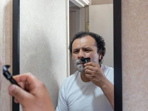 Man with a pained expression while shaving his face Stock Photos