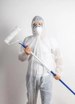 Man with paint roller dressed in white protective suit Stock Photos