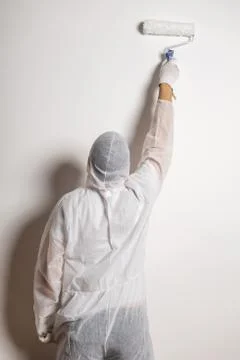 Man with paint roller dressed in white protective suit Stock Photos