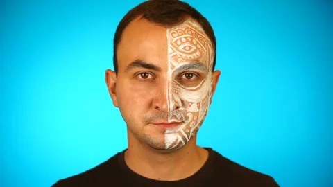 Man with painted face is looking at camera on blue background Stock Footage 159991668