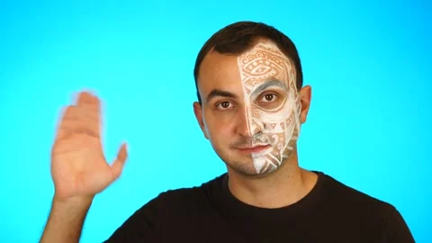 Man with painted face is waving hand and looking at camera against blue Stock Footage 160477332