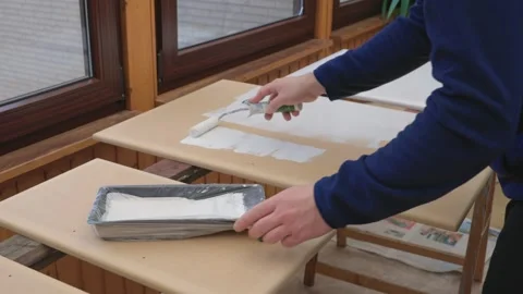 A man, a painter, a carpenter, a hired worker paints a board. Male hands roll Stock Footage 304881444