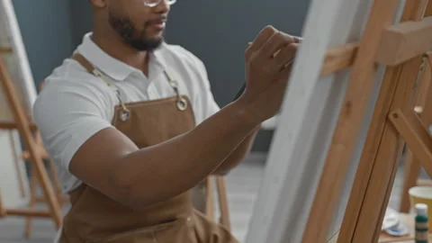 Man painter painting on canvas with hand holding brush at easel in studio, .. Stock Footage 337439170