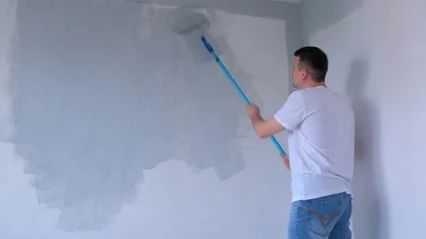 Man painter is painting wall in gray using paint rollers in new flat himself. Stock Footage 136216696