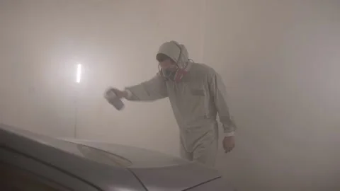 A man painter paints a car with a spray can of paint in a spray booth. Car Stockbeeldmateriaal 295105348