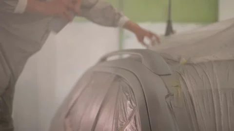 A man painter paints a car with a spray can of paint in a spray booth. Car Stock Footage 296579779