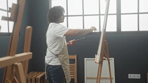 Man painter wearing apron holds paintbrush and palette while painting on ea.. Stock Footage 337398567