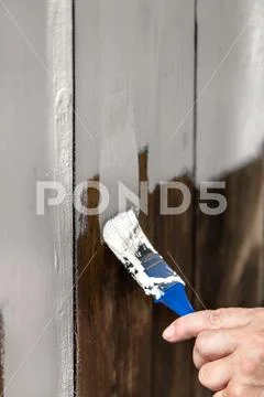 Man is painting and chalking a wooden fence, closeup with a paintbrush Stock Photos