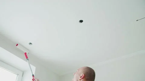 A man painting the ceiling white with a roller. DIY home repair. Stock Footage 148231391