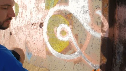 Man painting graffiti on wall on beach Video stock 82429656