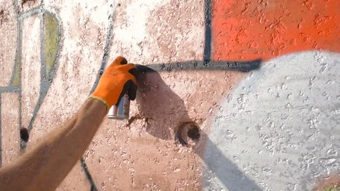Man painting graffiti on wall on beach Stock Footage 82430457