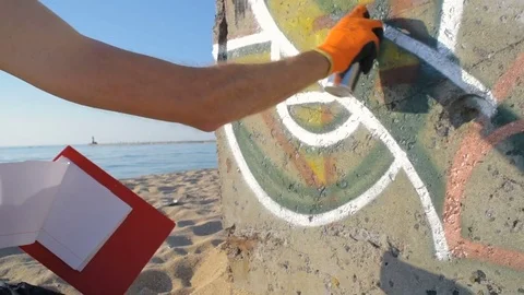 Man painting graffiti on wall on beach Video stock 82433474