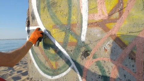 Man painting graffiti on wall on beach 库存影片 82433488