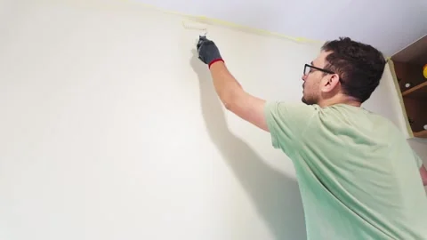 Man painting interior wall with roller in home renovation Stock Footage 335315784