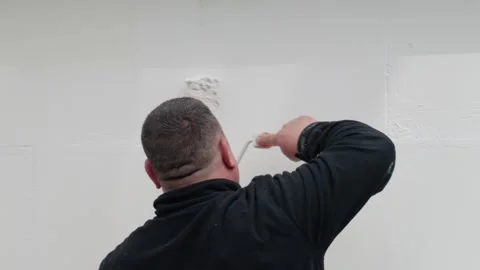 Man painting wall with roller applying white paint outdoor on textured surfac Stock Footage 339755150
