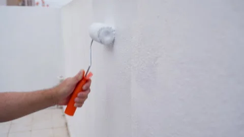 Man painting white wall on rooftop terrace during home makeover project. Mo.. Stock Footage 334549556
