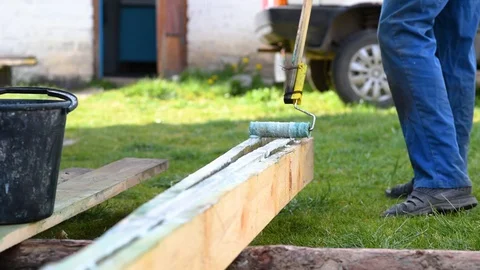Man paints boards with a roller on a stick Stock Footage 129082376