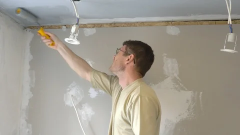 A man paints the ceiling with a roller gray paint. Stock Footage 107262678