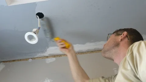 A man paints the ceiling with a roller gray paint. Stock Footage 107262686
