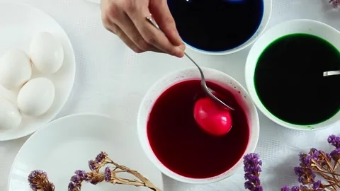 A man paints easter eggs in white plates in multicolored colors, minimalist Stock Footage 171788483