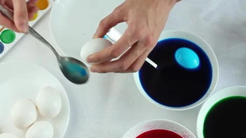 A man paints easter eggs in white plates in multicolored colors, minimalist Video stock 171788557