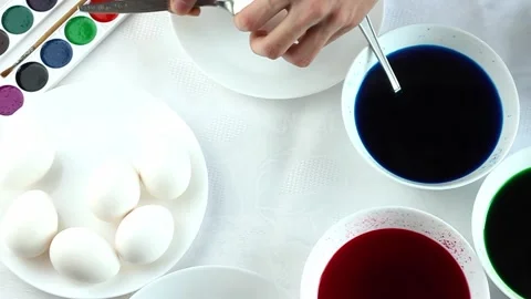 A man paints easter eggs in white plates in multicolored colors, minimalist Stock Footage 171959335