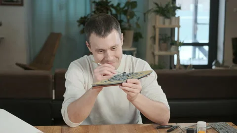 Man paints elements plastic model of warship  of layout with brush. Stock Footage 168894182