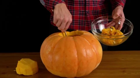 Man paints pumpkin for Halloween while sitting in dark room. Preparing Stock Footage 272459809