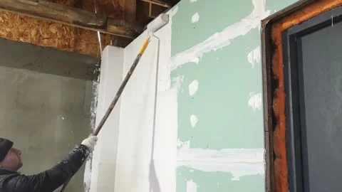 Man paints wall in indoor space during renovation project in winter season Video stock 326377516