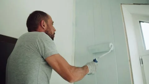 A man paints a wall with a roller. A man makes repairs in the room. Modern Stock Footage 157262456