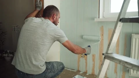 A man paints a wall with a roller. A man makes repairs in the room. Modern Stock Footage 157272478