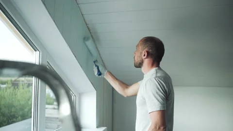 A man paints a wall with a roller. A man makes repairs in the room. Modern Stock Footage 157274457
