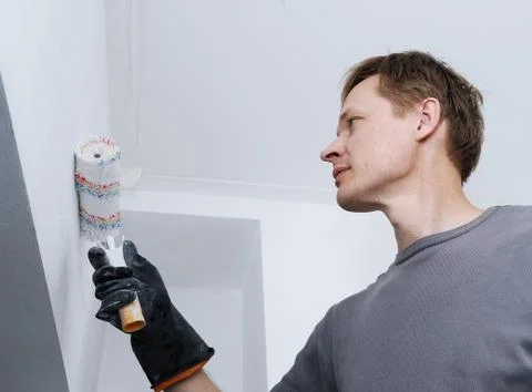 Man paints a wall with a roller. Stock Photos