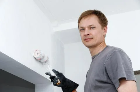Man paints a wall with a roller. Stock Photos