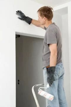 Man paints a wall with a roller Stock Photos