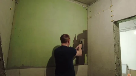Man paints wall in room during home renovation project in simple space Stock Footage 332479613